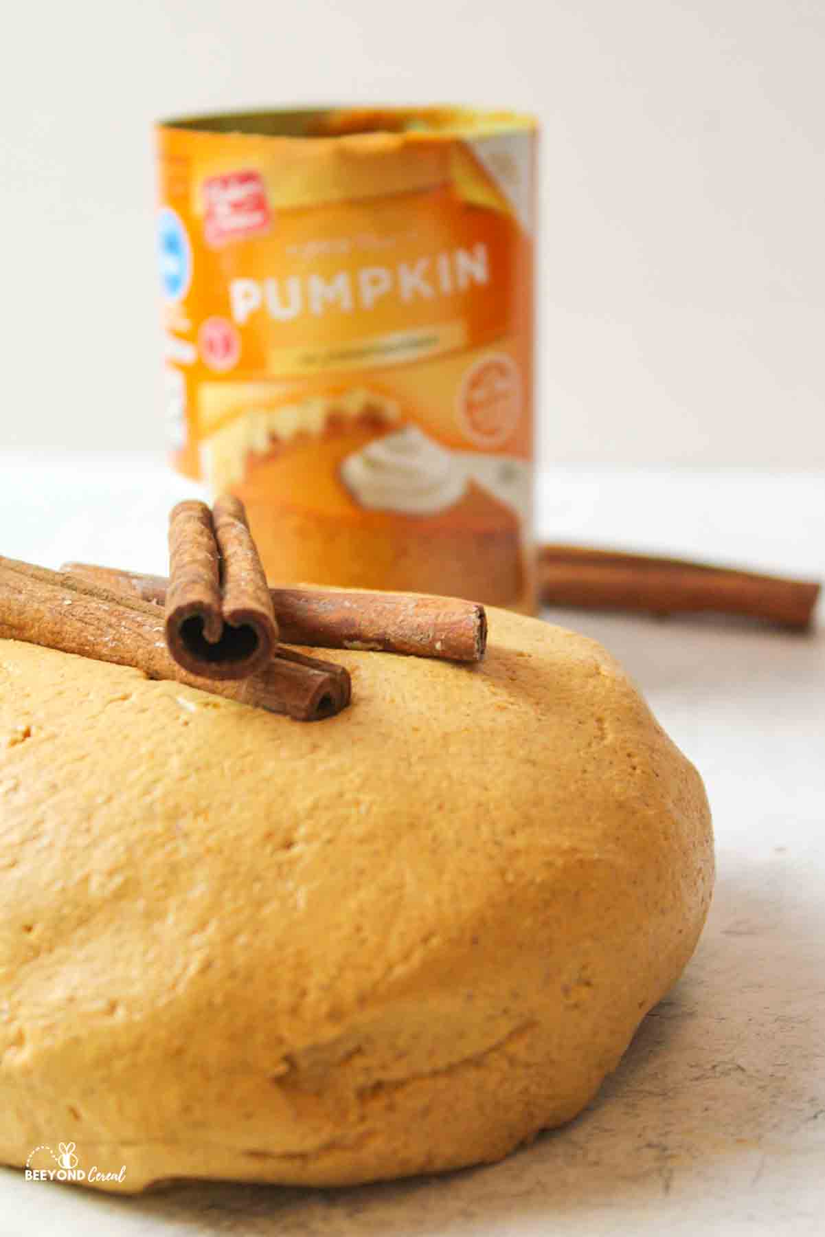 a large ball of pumpkin playdough with cinnamon sticks on top and a can of pumpkin puree in the background