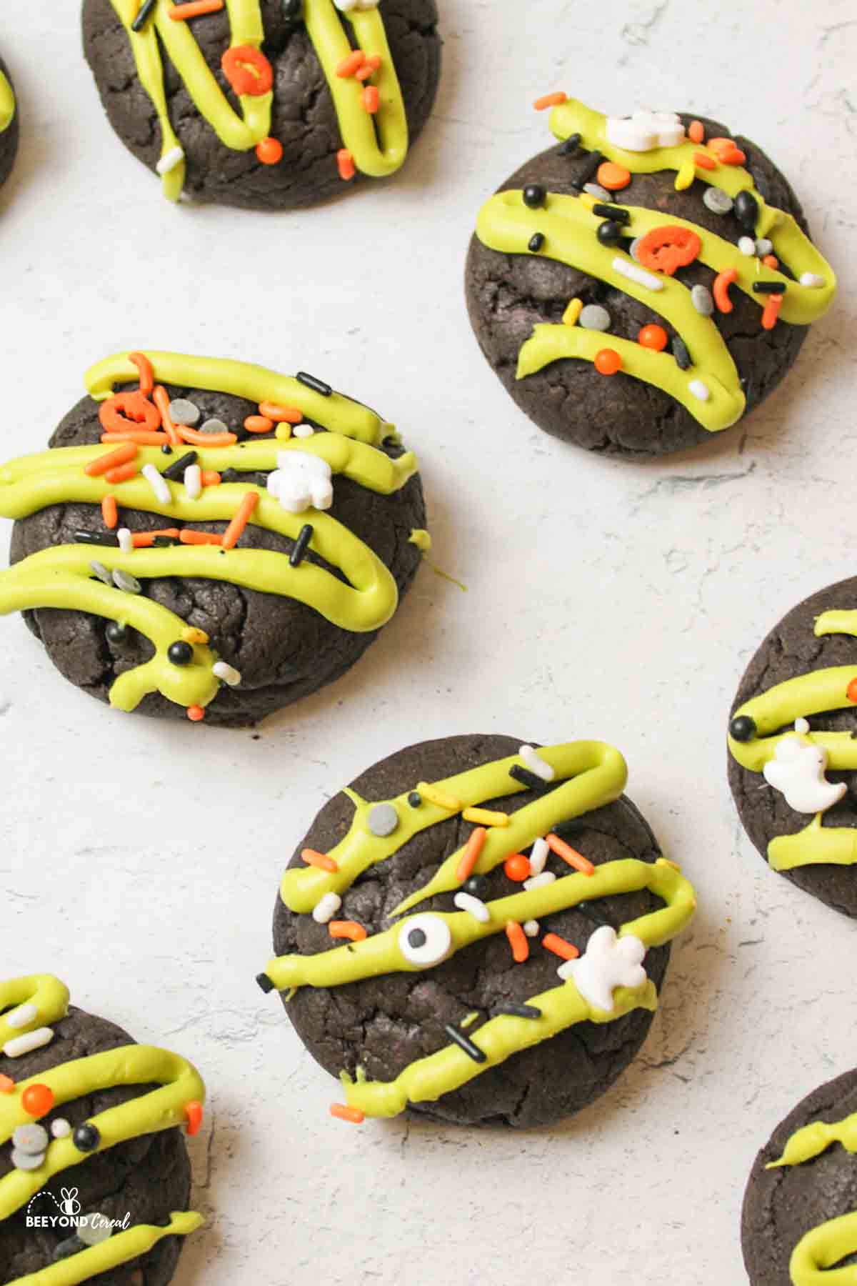 scattered halloween cookies with green drizzle and sprinkles on top