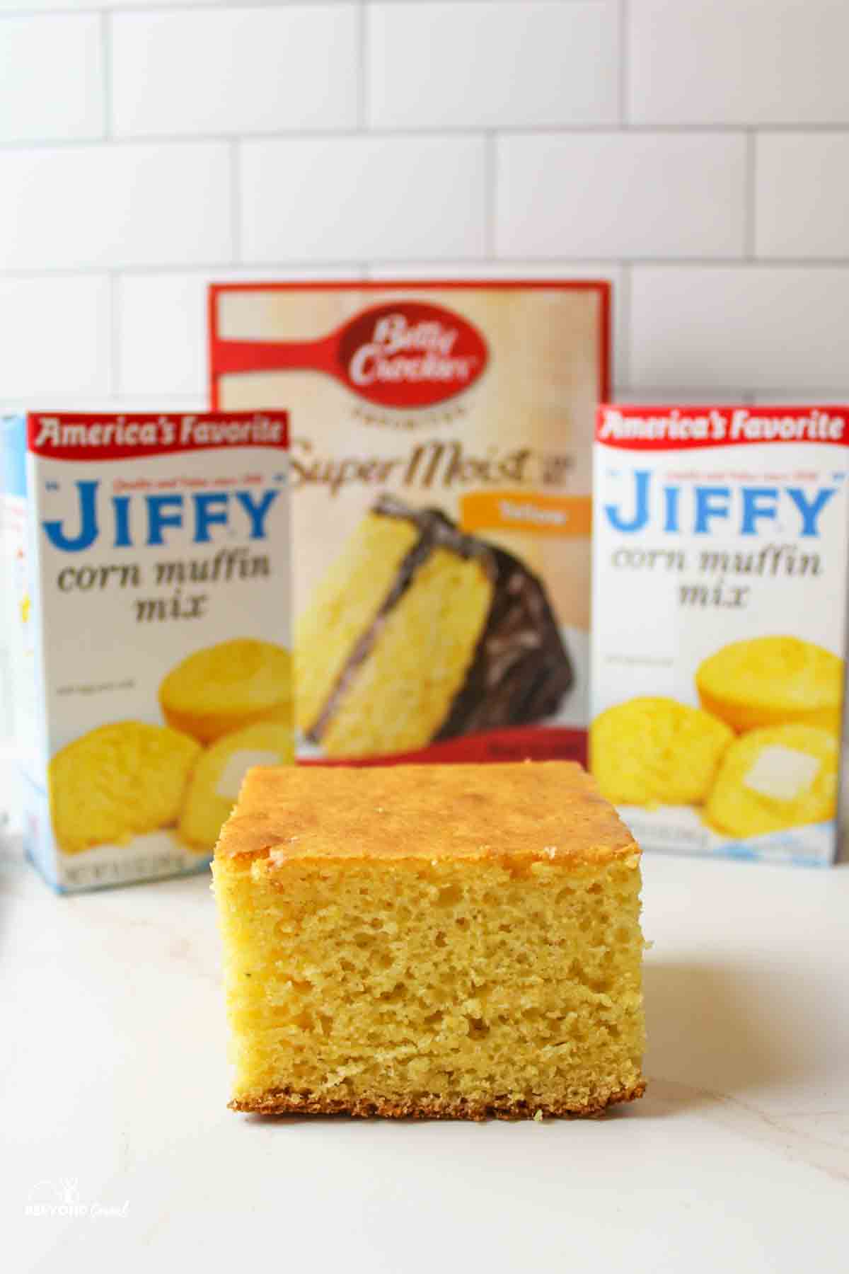 Cornbread slice in front of Jiffy corn mix, yellow cake.