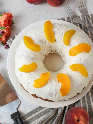 a peaches and cream bundt cake with forks and a server to the side.