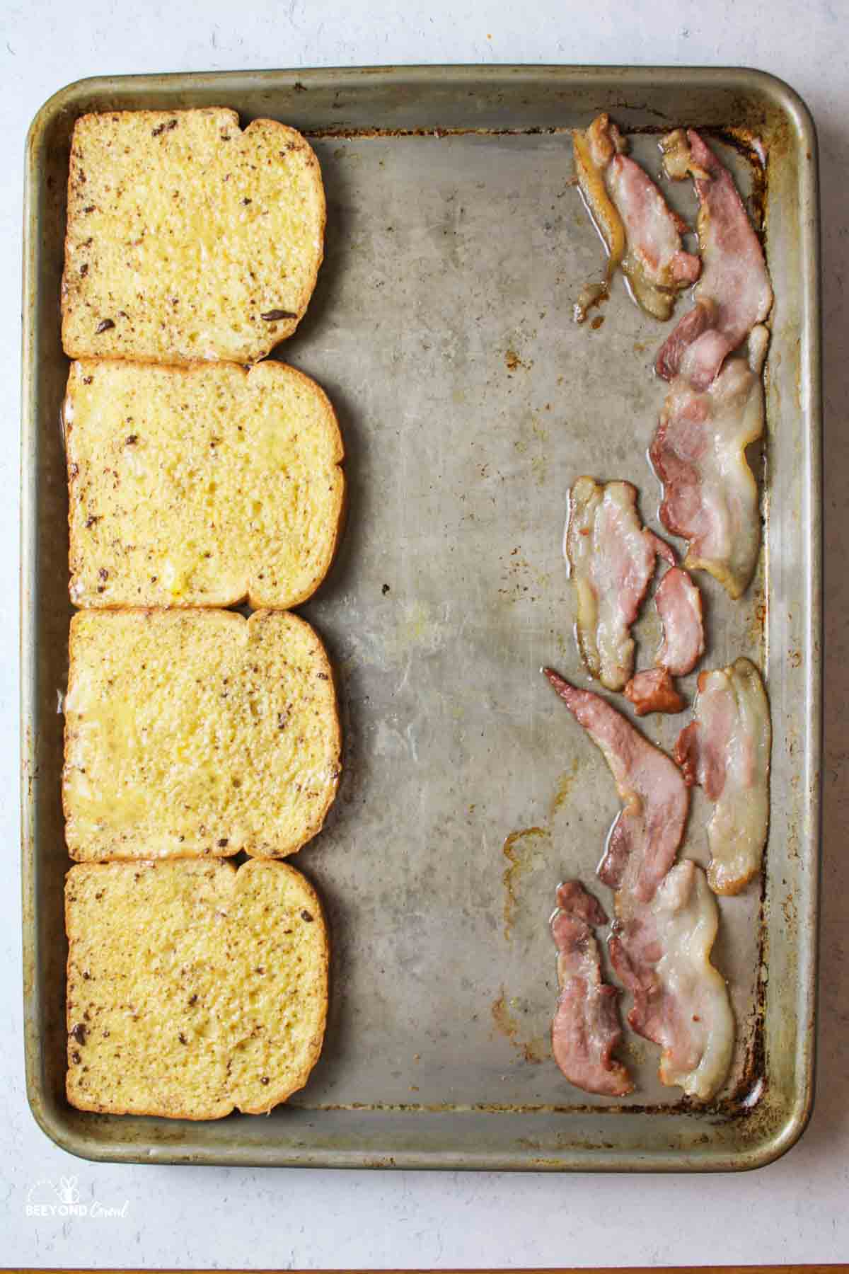 raw french toast and bacon on a baking sheet.