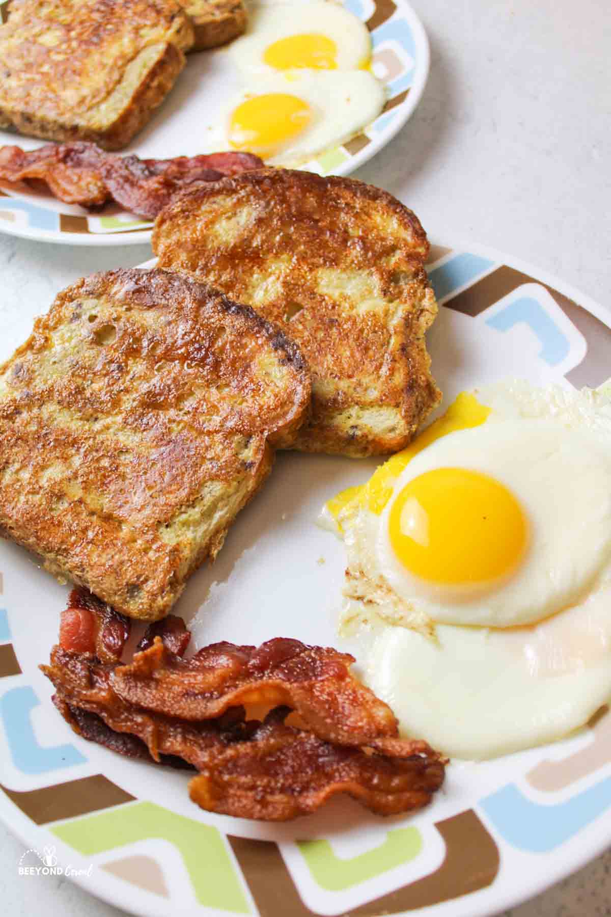 eggs, bacon, and french toast on plates.