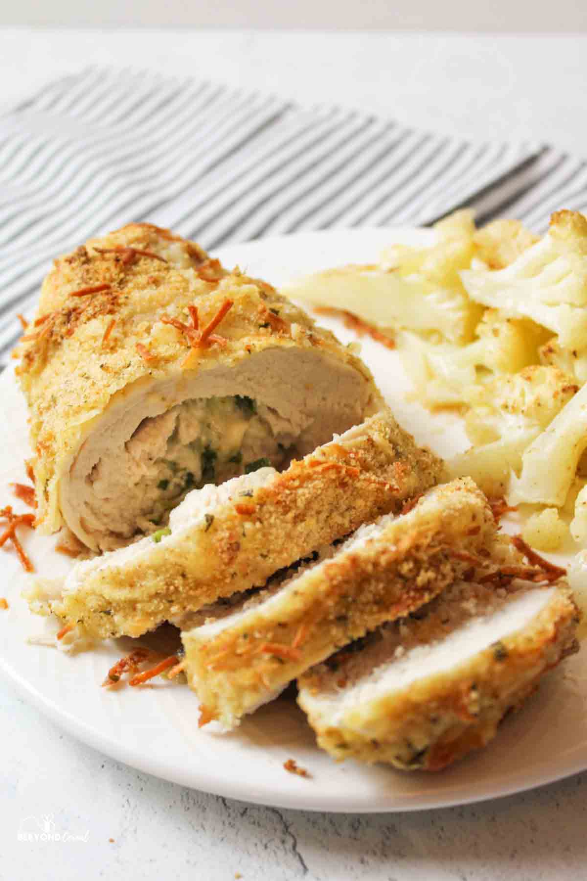 a sliced cheese stuffed chicken roll up on a plate.