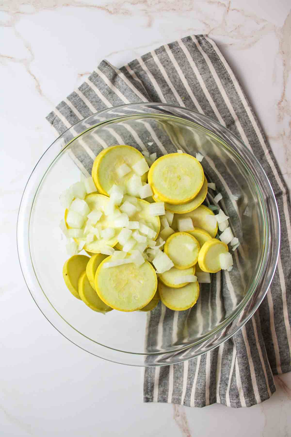 sliced yellow squash and diced onions in a mixing bowl.