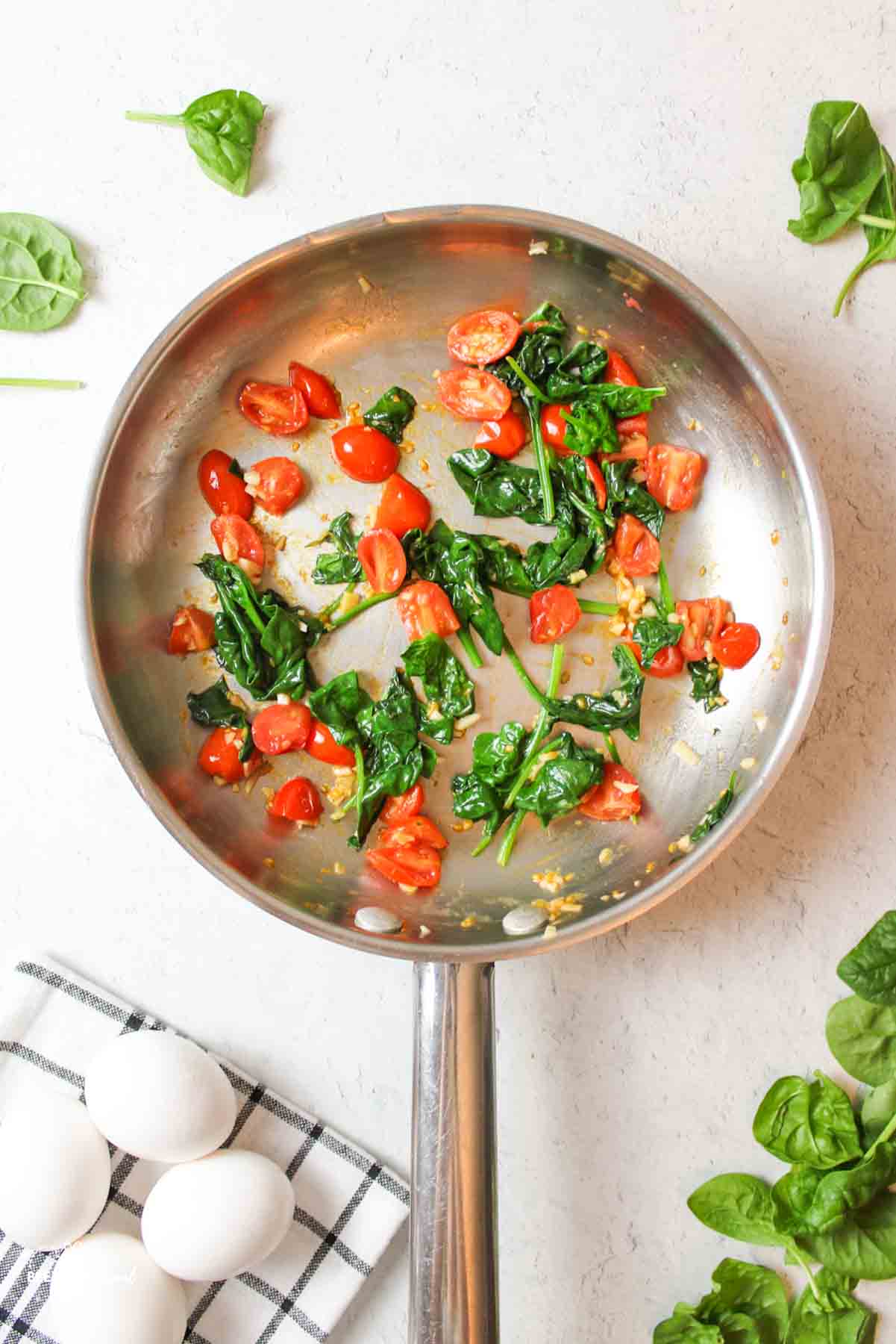 cooked spinach and tomatoes in a skillet