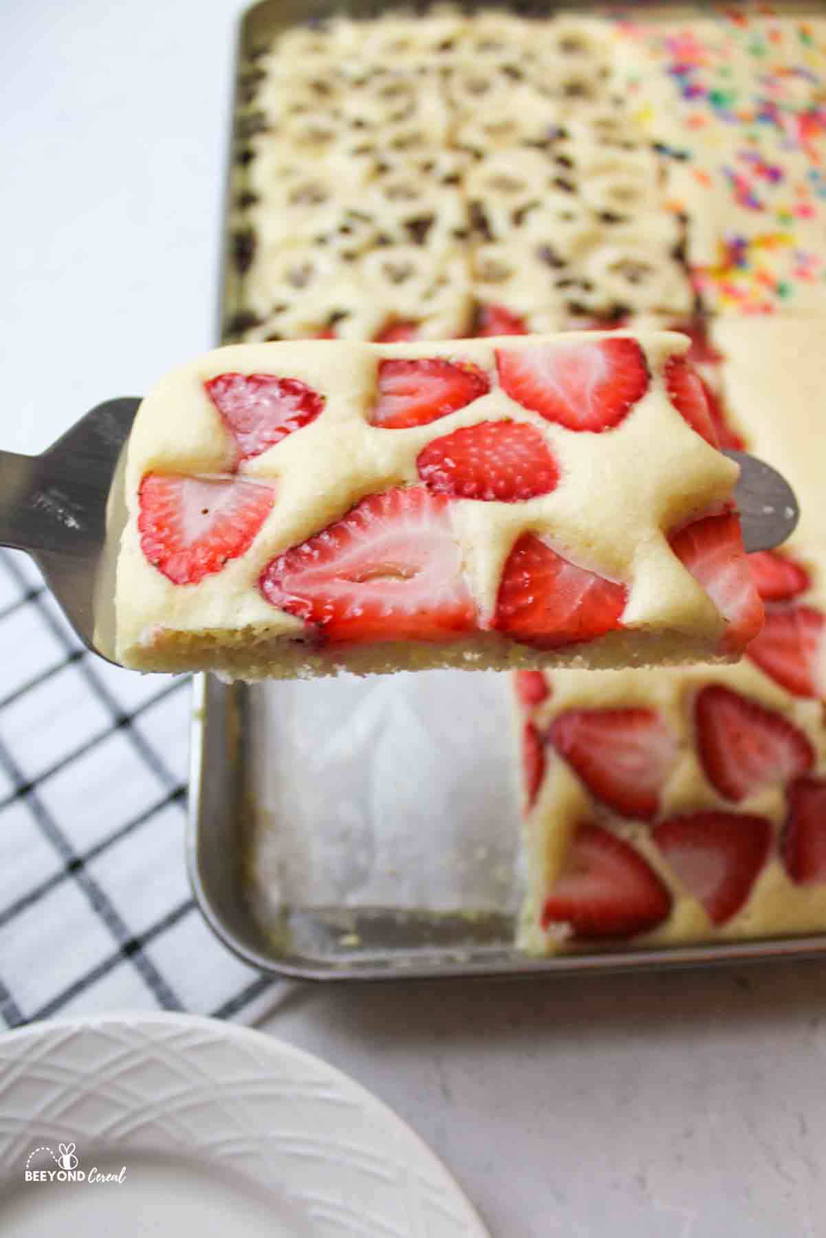 lifting a strawberry pancake from the sheet pan.