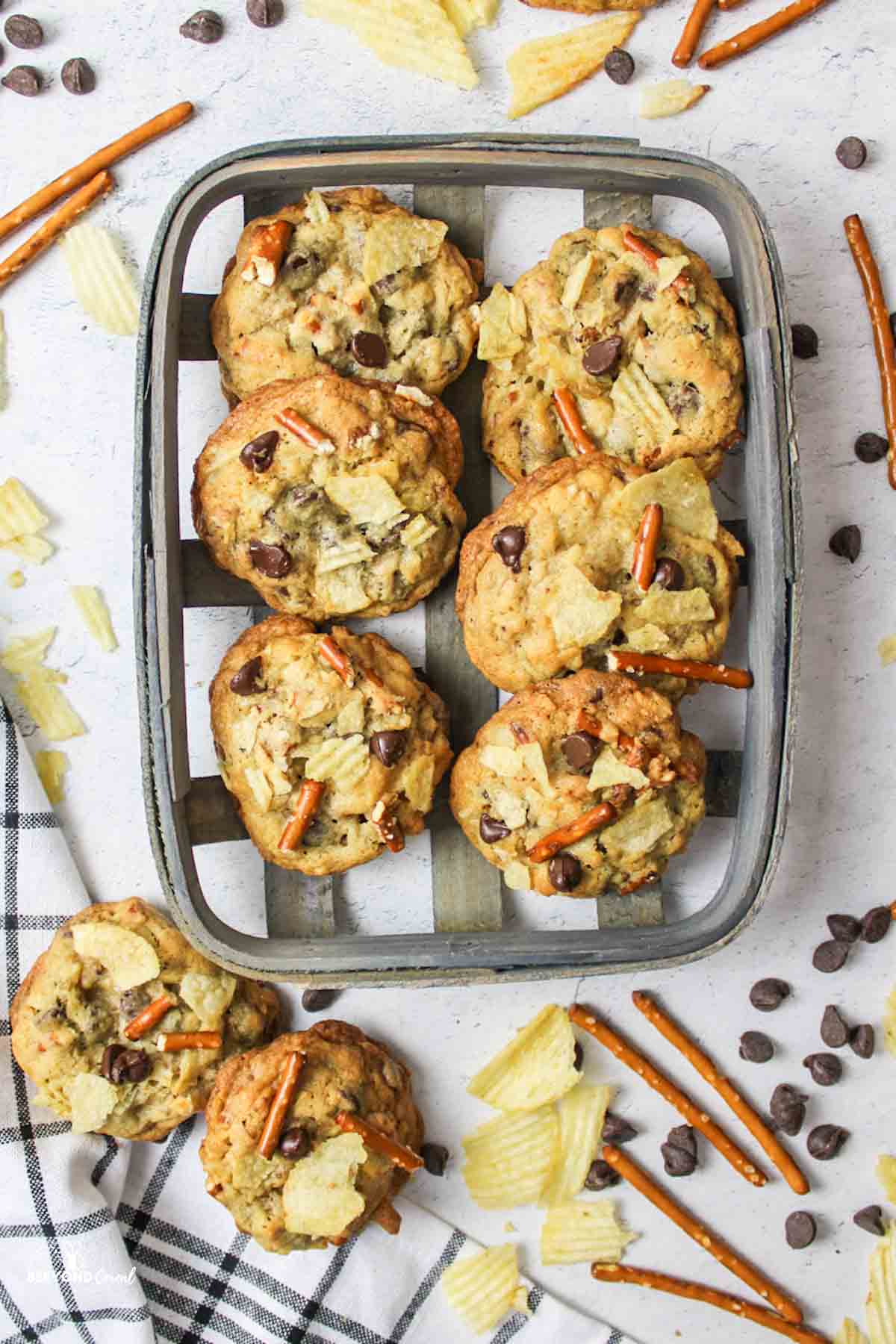 chococlate chip pretzel cookies with chips in a basket with more cookies and ingredients around it