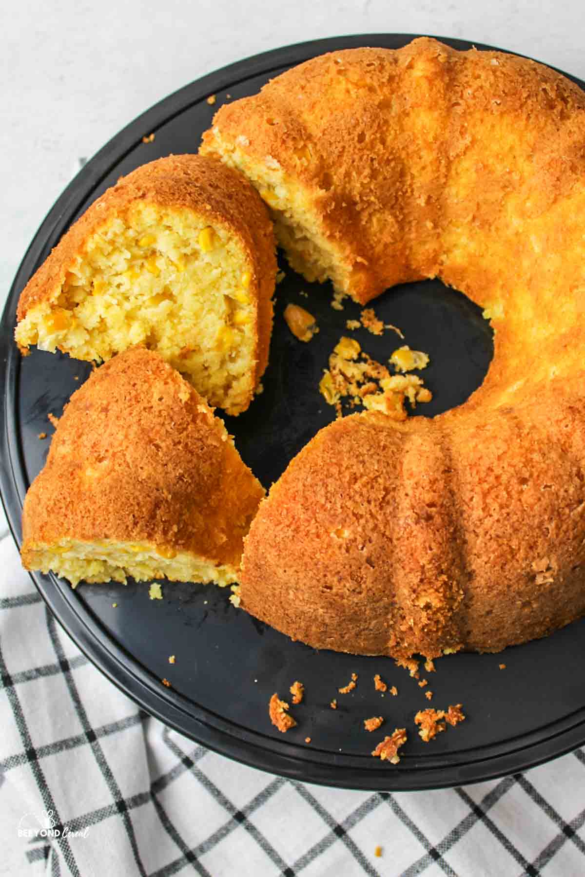 Two sliced pieces of cornbread bundt cake arranged beside the whole cake.