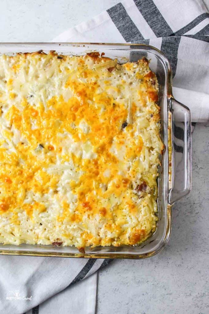 half of a glass baking dish filled with cheesy hashbrown casserole