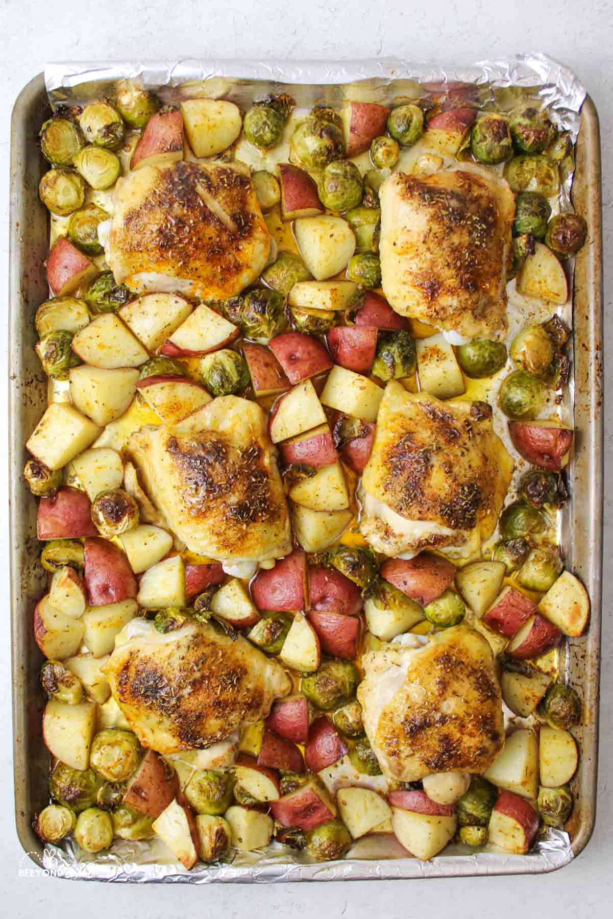 cooked chicken brussel sprouts and potatoes on a sheet pan.