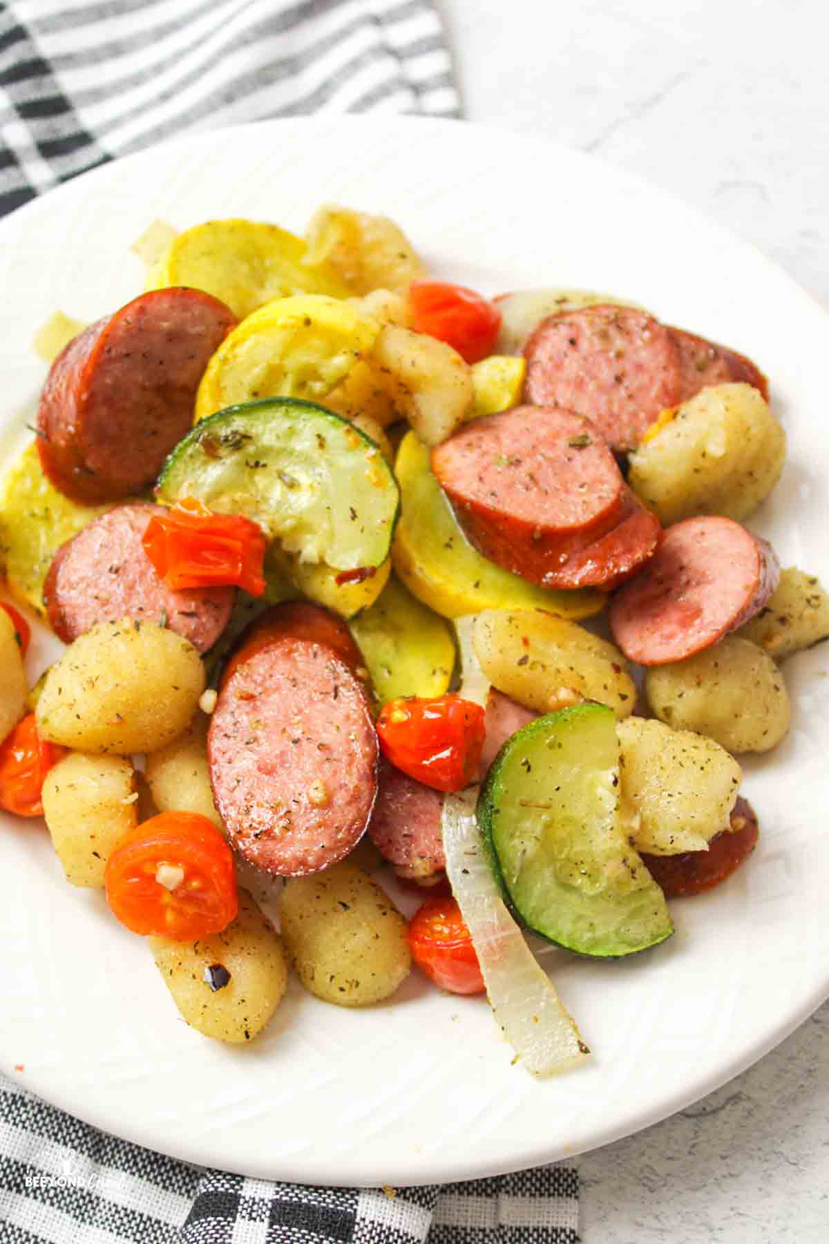a dinner plate filled with gnocchi with sausage and vegetables