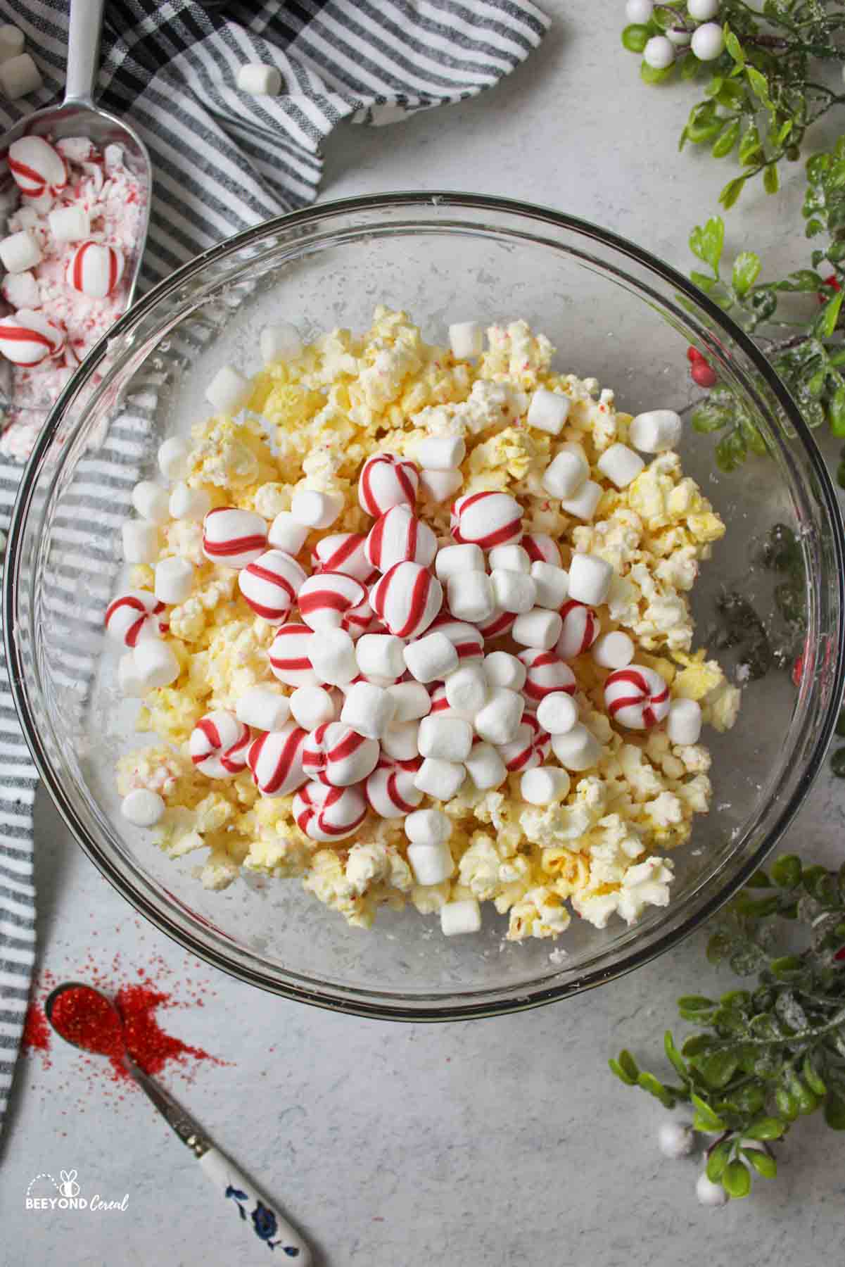 a popcorn in bowl topped with mini marshmallows and sweet stripes peppermint balls.