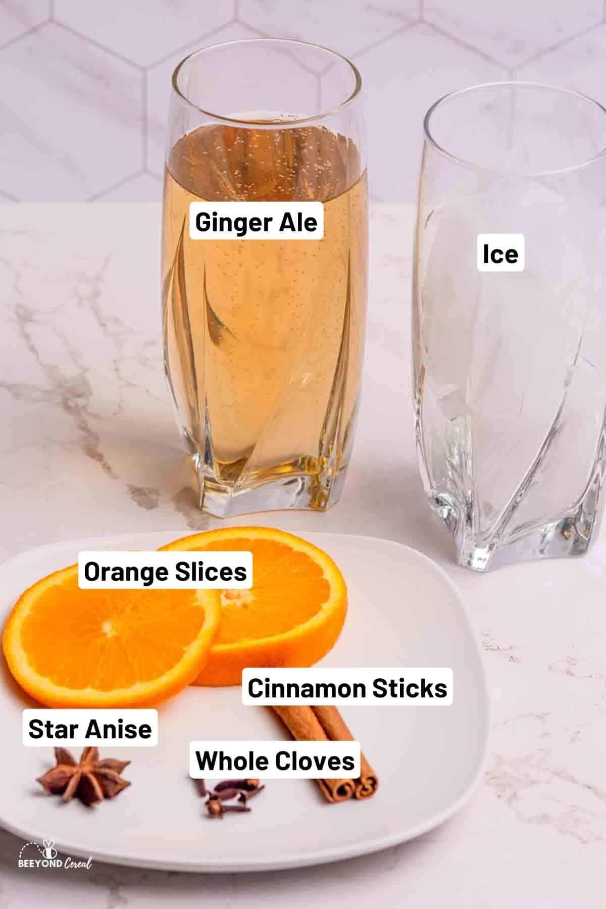 a glass of ice next to a glass of ginger ale and orange slices and spices on a plate.