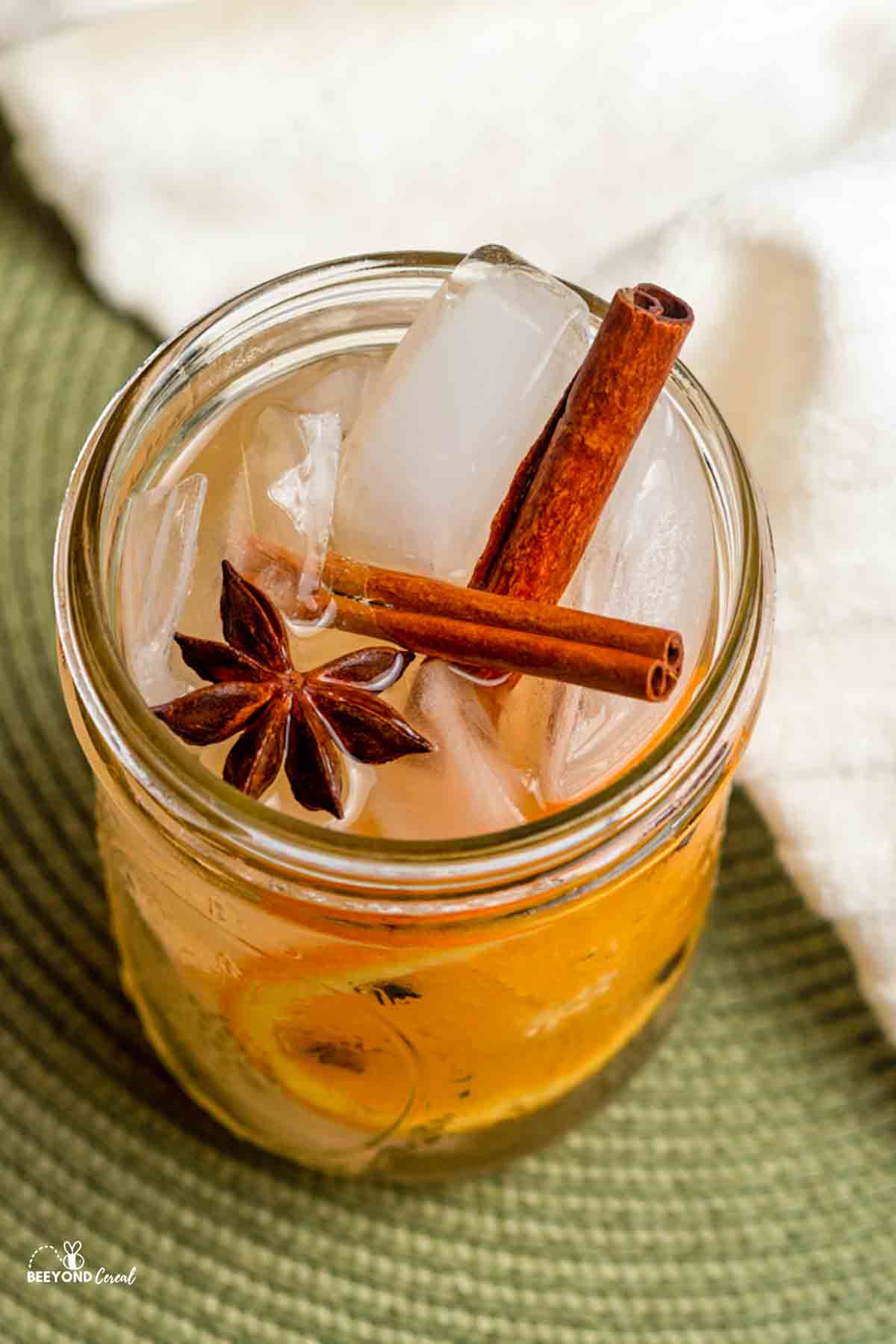two cinnamon sticks and a star anise in an iced jar of spiced ginger ale.