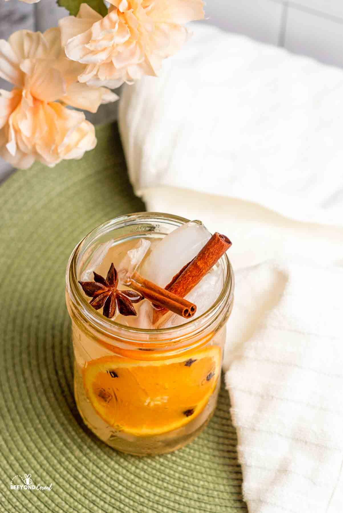 a star anise and two cinnamon sticks in a mason jar full of gingerale and orange slice