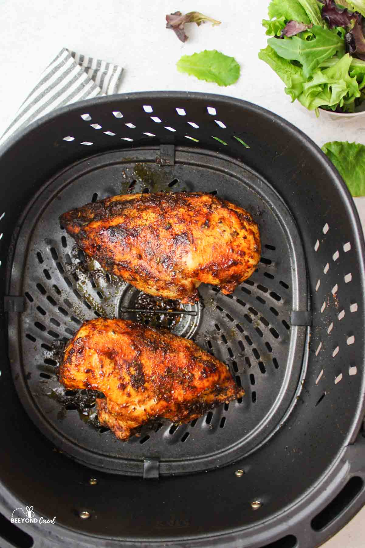 two cooked chicken breasts in an air fryer.