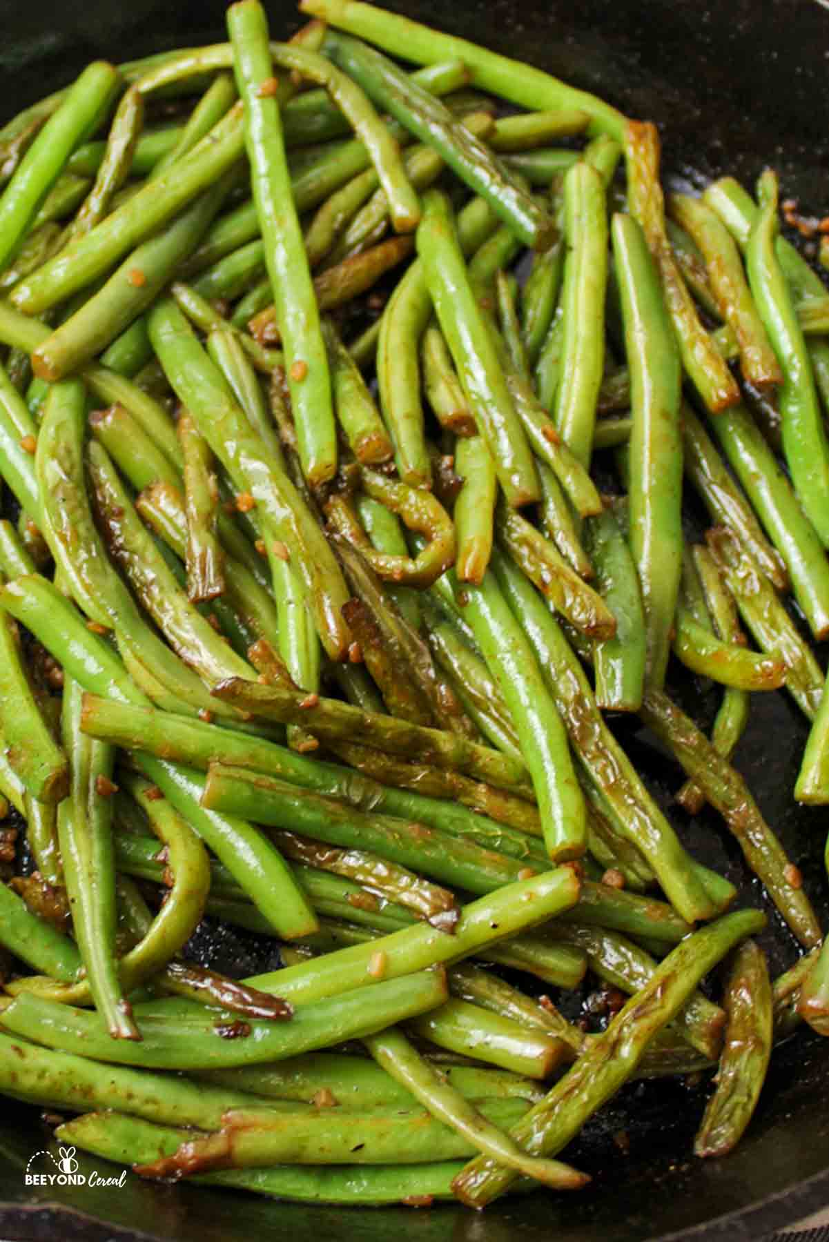 an upclose view of cooked green beans in a cast iron skillet
