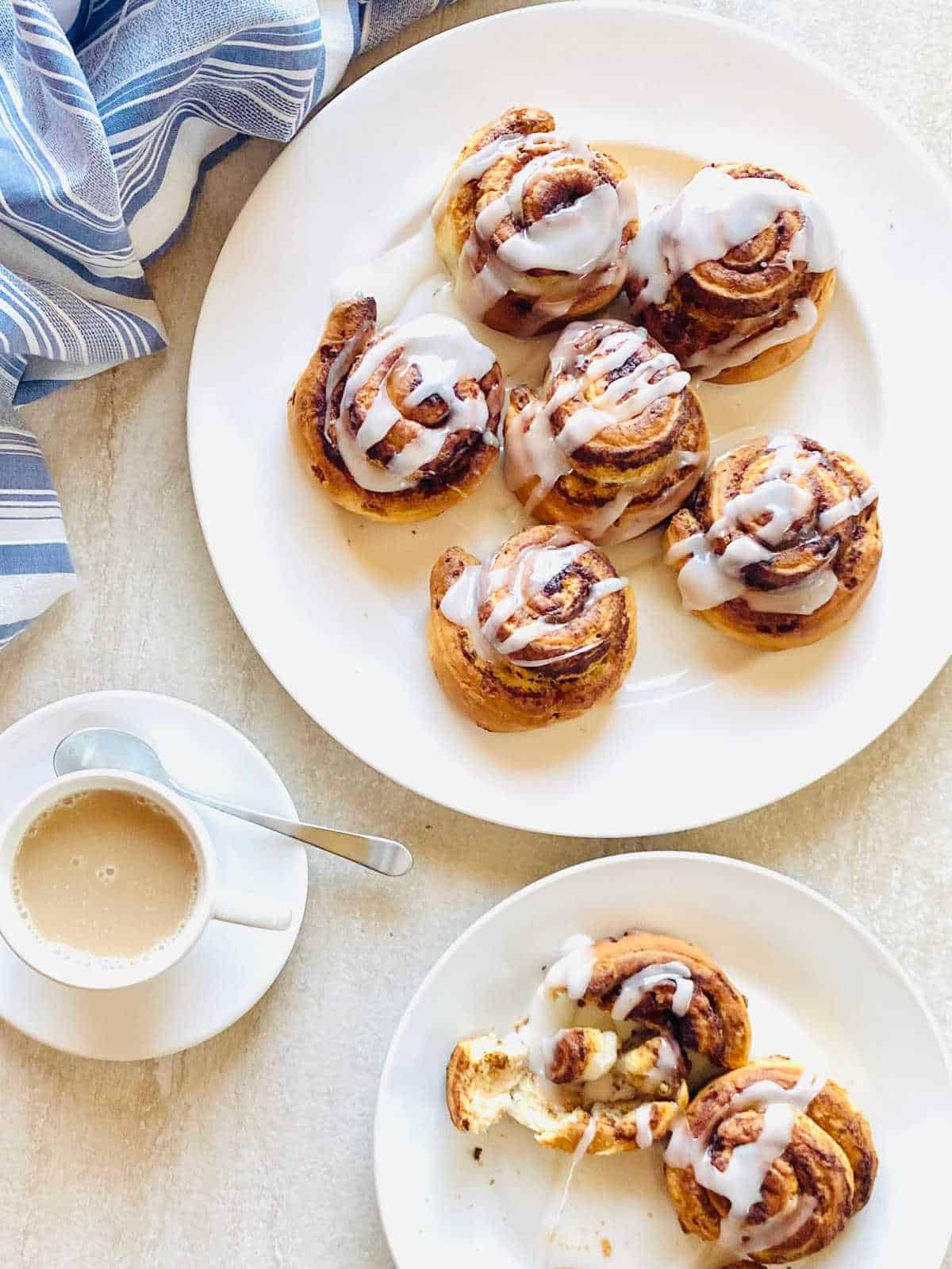 air fried cinnamon rolls on plates with icing drizzled over the top