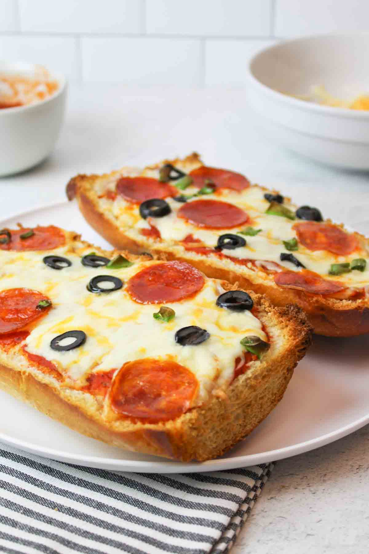 two baked halves of french bread pizza on a white plate.