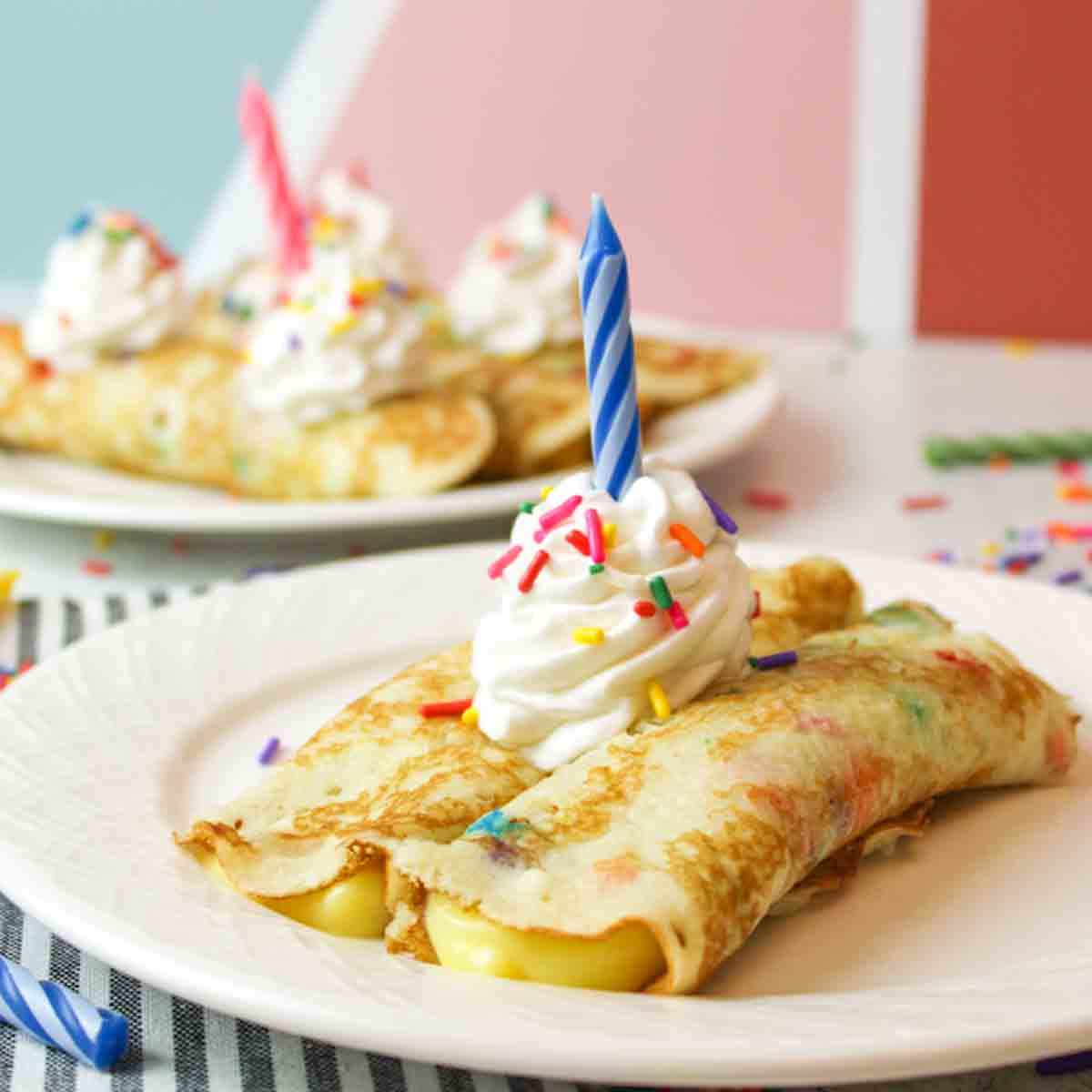 birthday cake crepes with whipped cream and a candle.