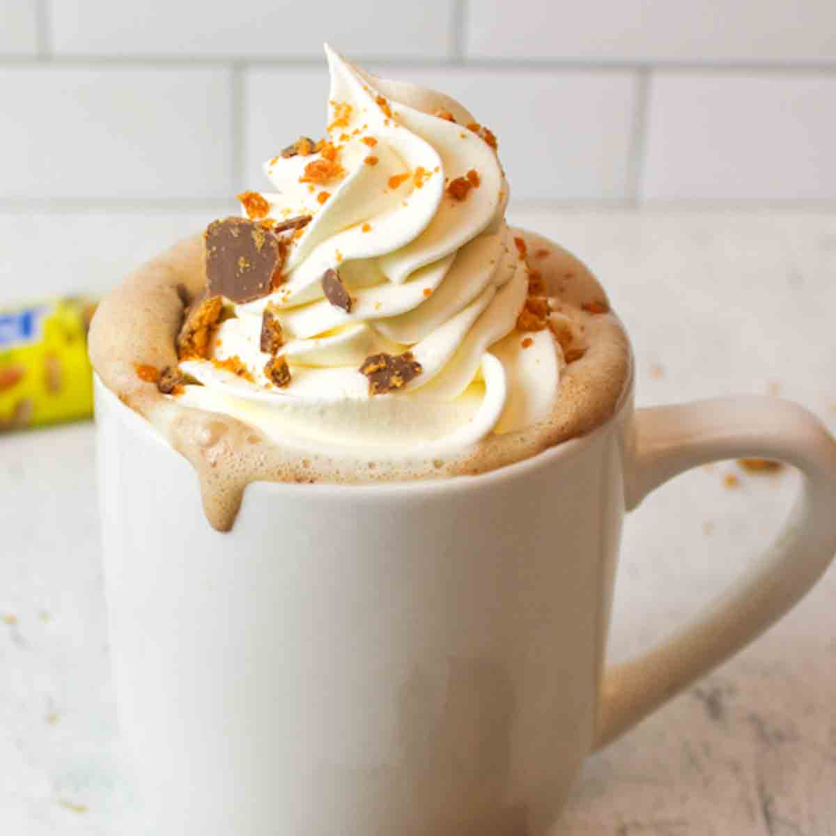 a cup of butterfinger hot chocolate with whipped cream and butterfinger crumbs.