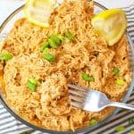 a bowl of shredded enchilada sauce chicken with a fork.