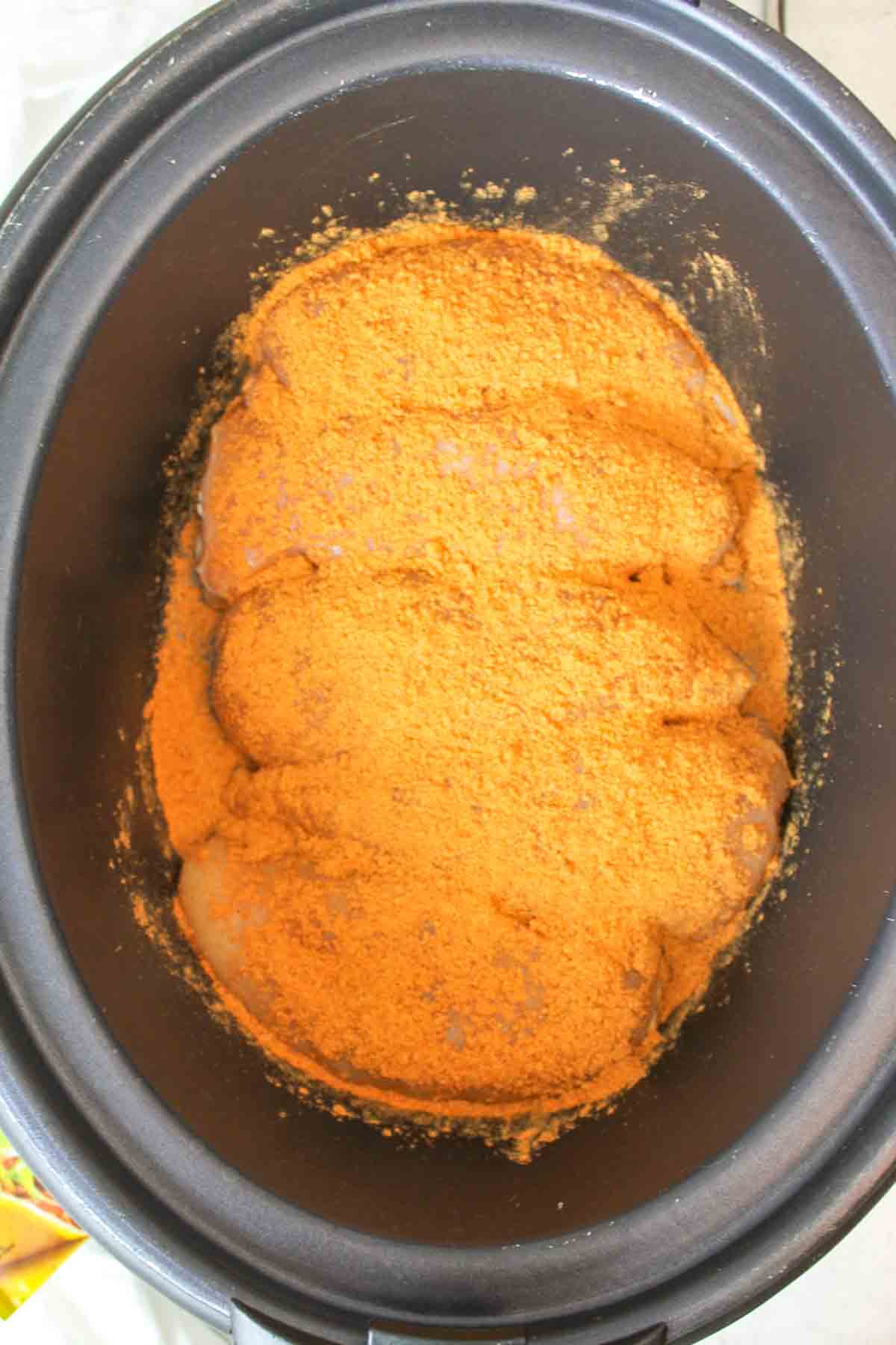 chicken breasts topped with taco seasoning in a crockpot.