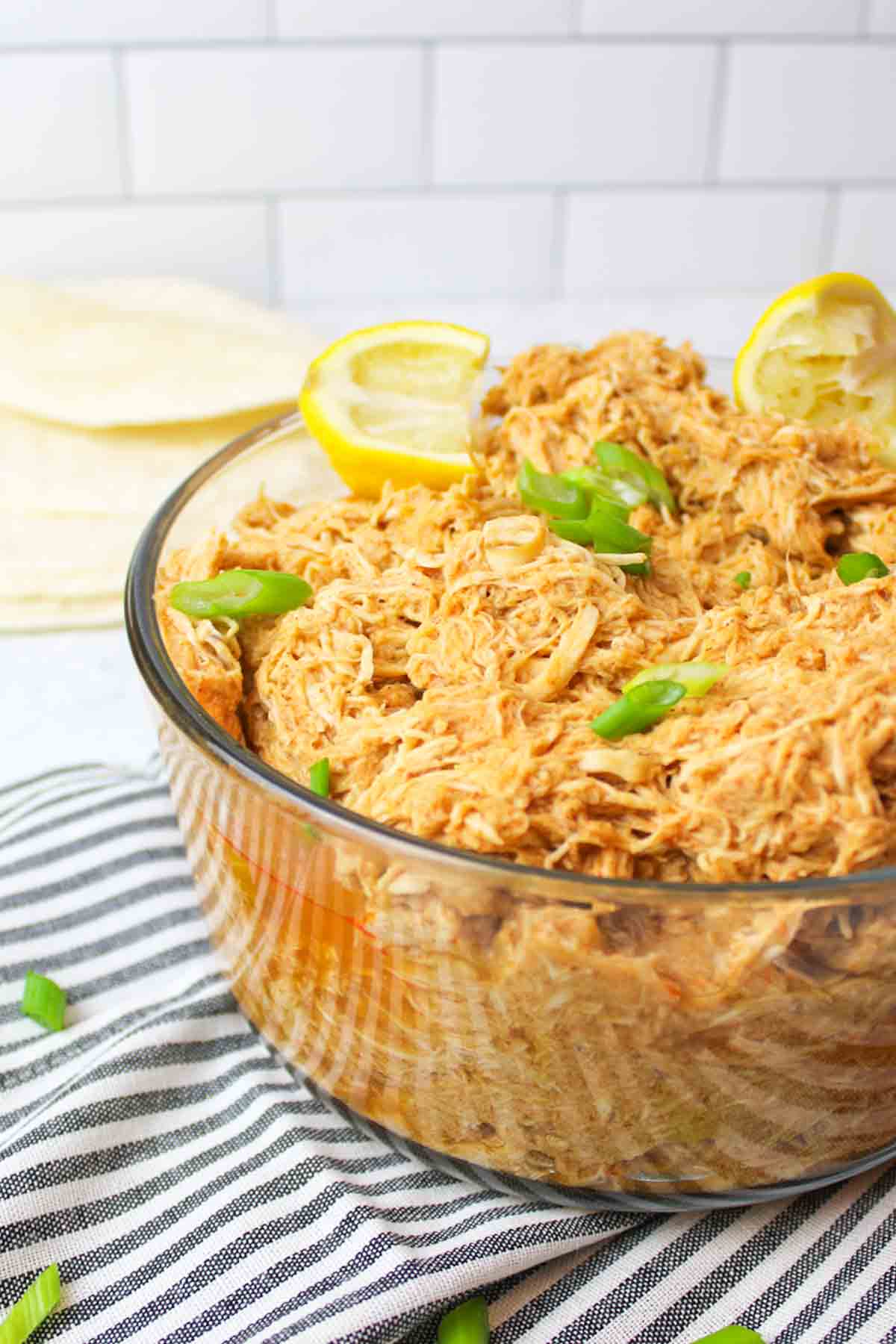 a glass bowl filled with shredded enchilada chicken.