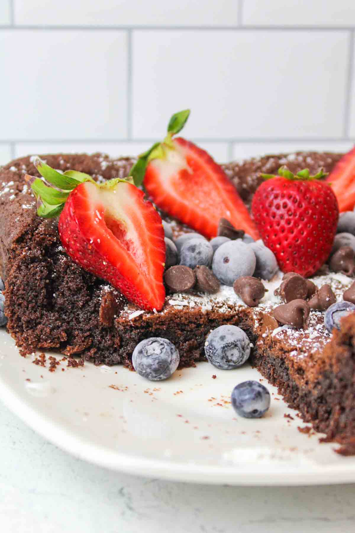 a cut portion of Devils Food Cake Brownies topped with fresh berries and chocolate chips