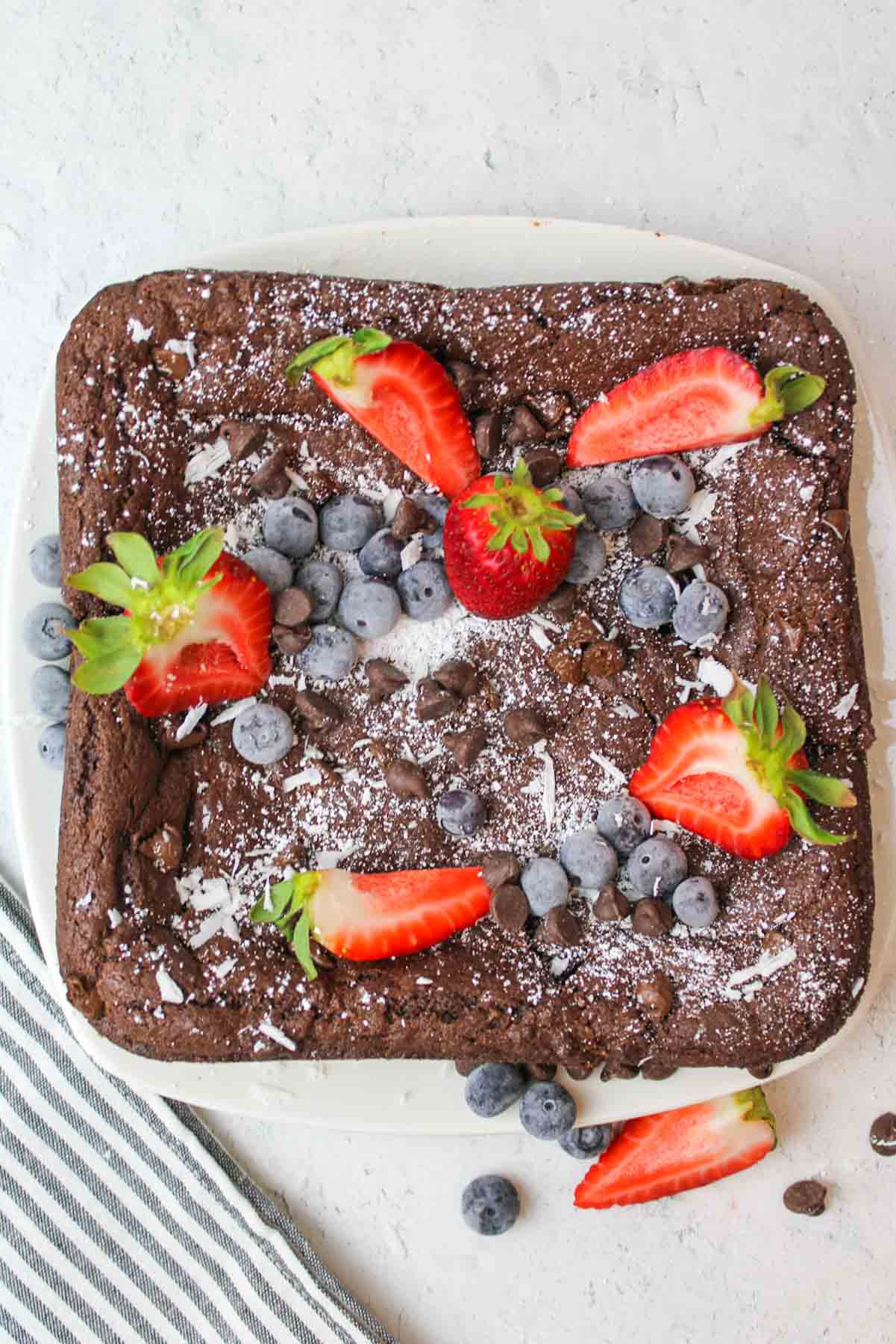 Devils Food Cake Brownie on a plate topped with powdered sugar and fresh berries.