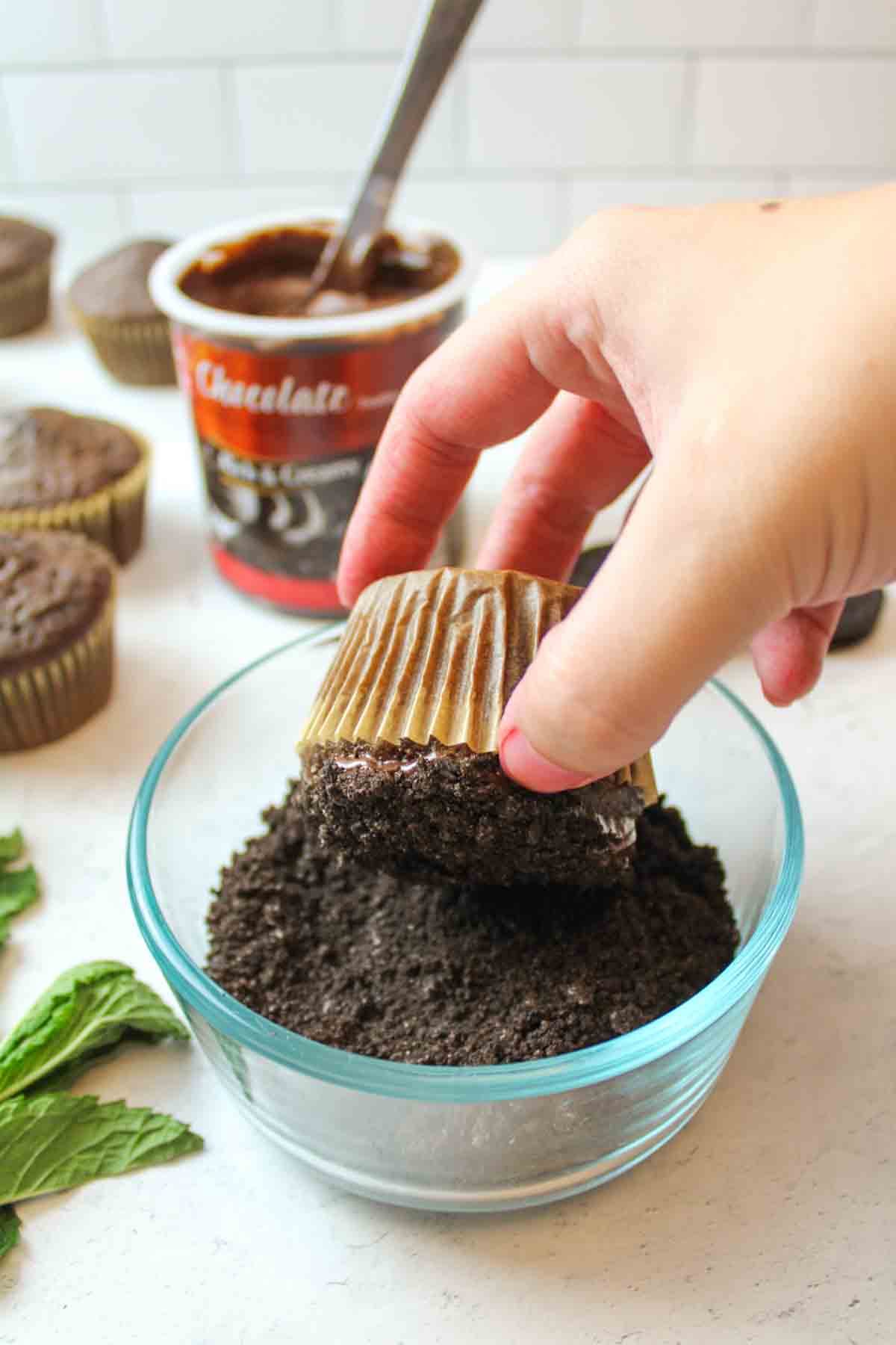 dipping the chocolate cupcakes in oreo crumb mixture