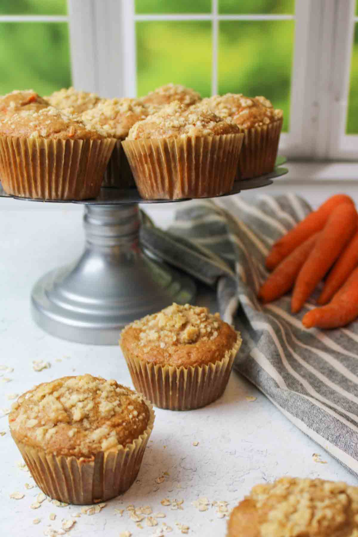 a cake stand with carrot muffins on and around it.