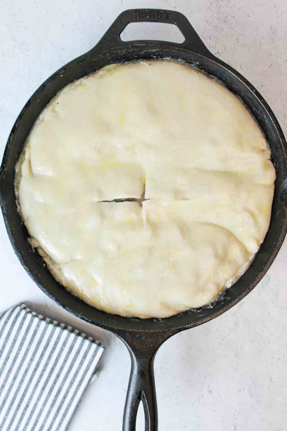 pie crust on ground beef pot pie filling in cast iron skillet
