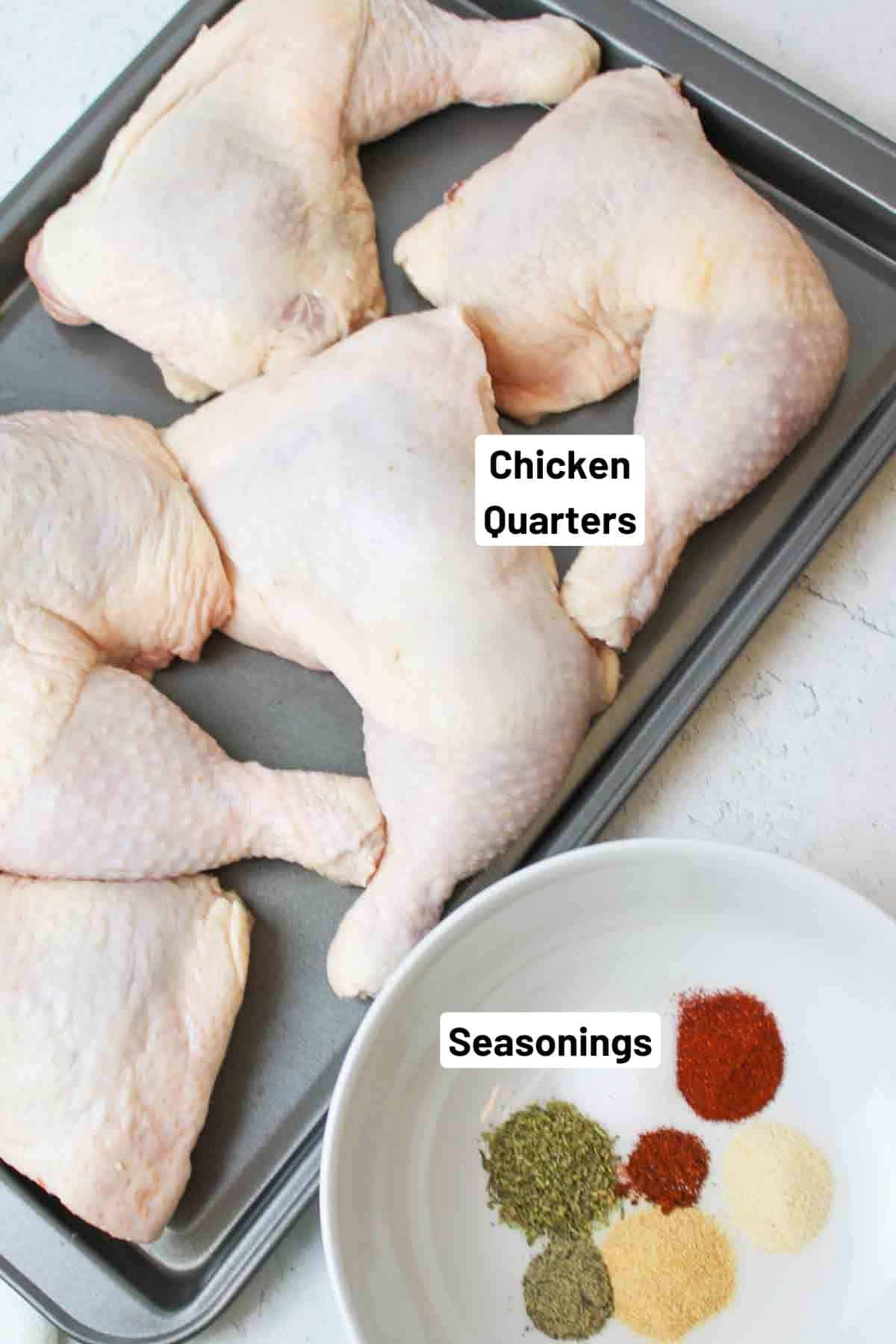 chicken quarters on a baking sheet next to a bowl with unmixed seasonings.