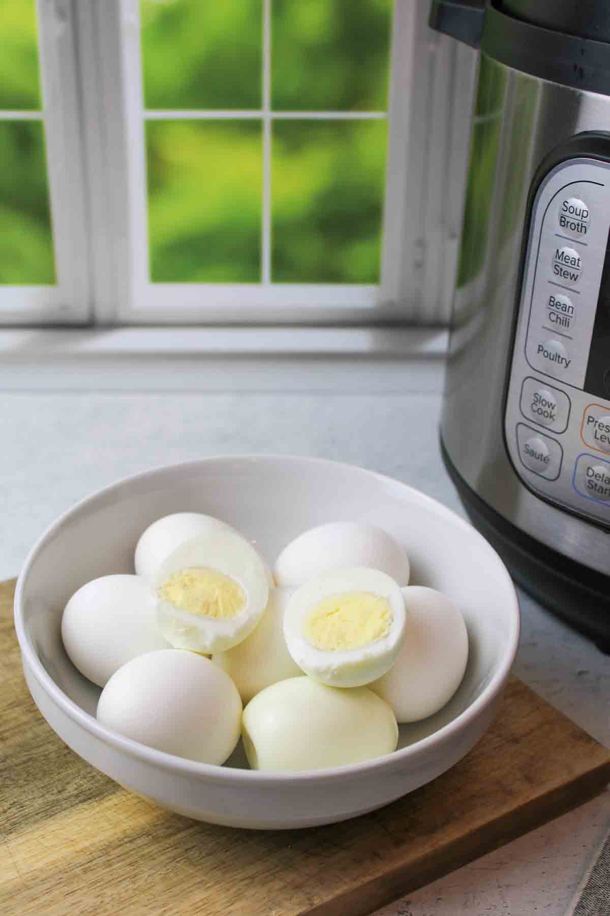 a bowl of hard boiled eggs next to an instant pot