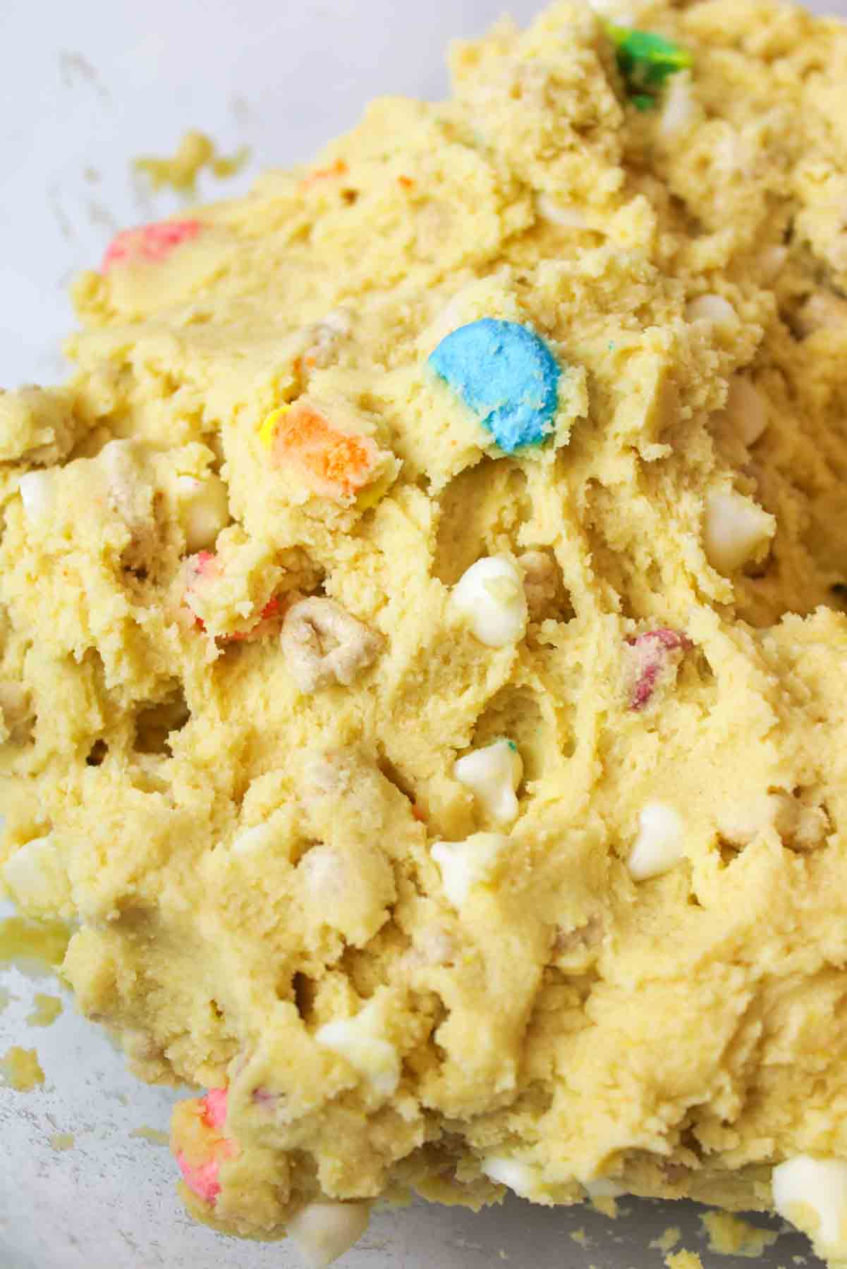 a close up of cookie dough with lucky charms and white chocolate chips inside of it.