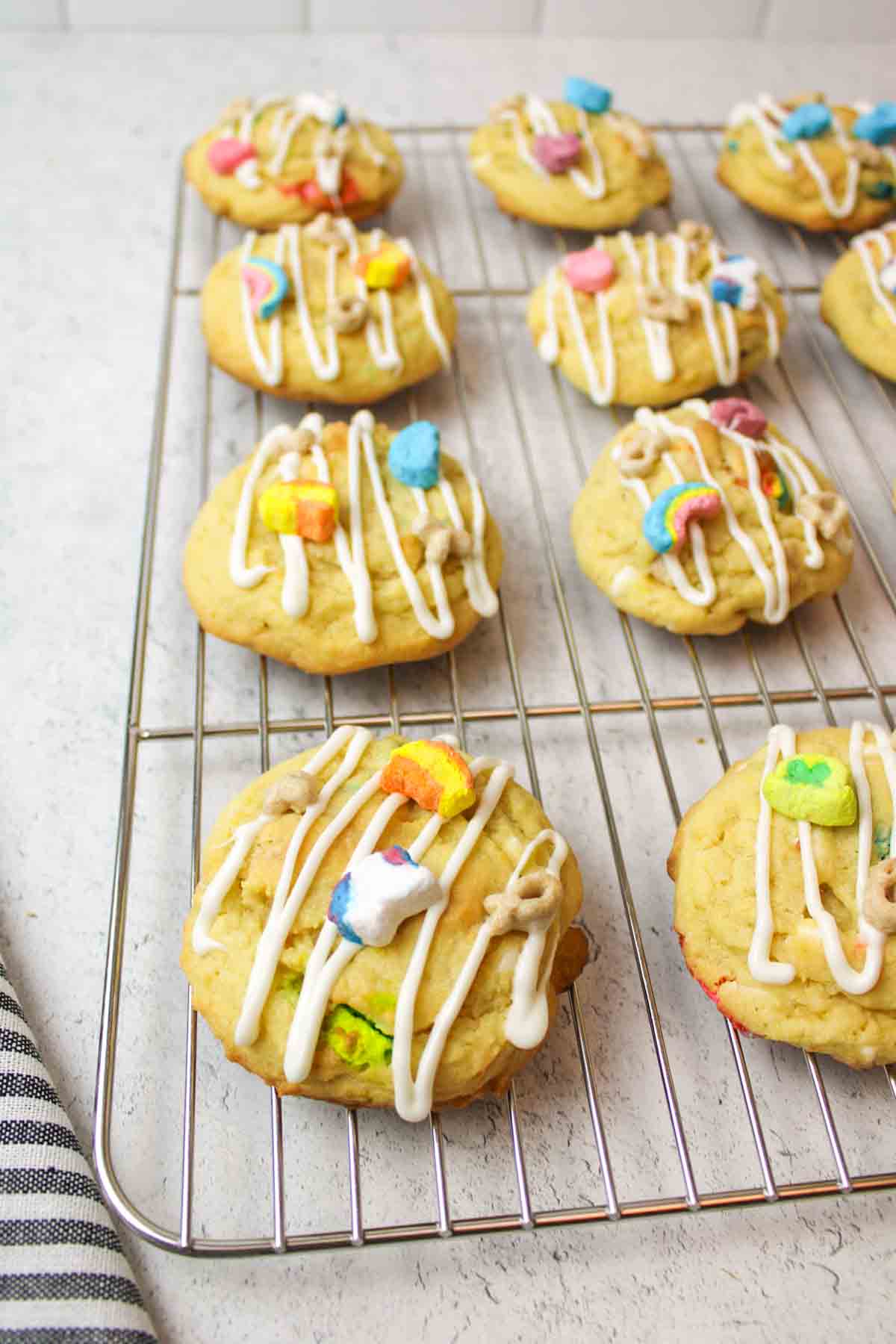 white chocolate drizzled on lucky charms cookies on a cooling rack.