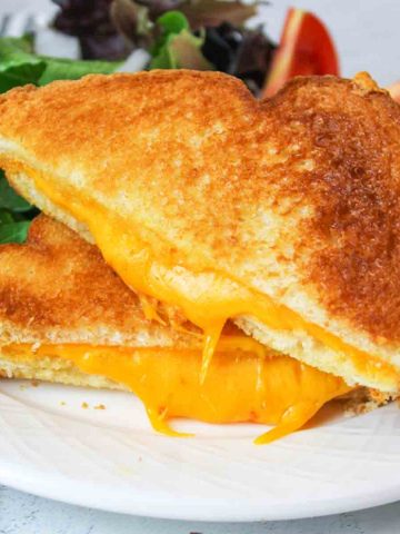 a close up of two halves of microwave grilled cheese sandwich with gooey melty cheese