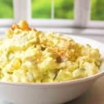 an upclose view of dill pickle potato salad in a white bowl