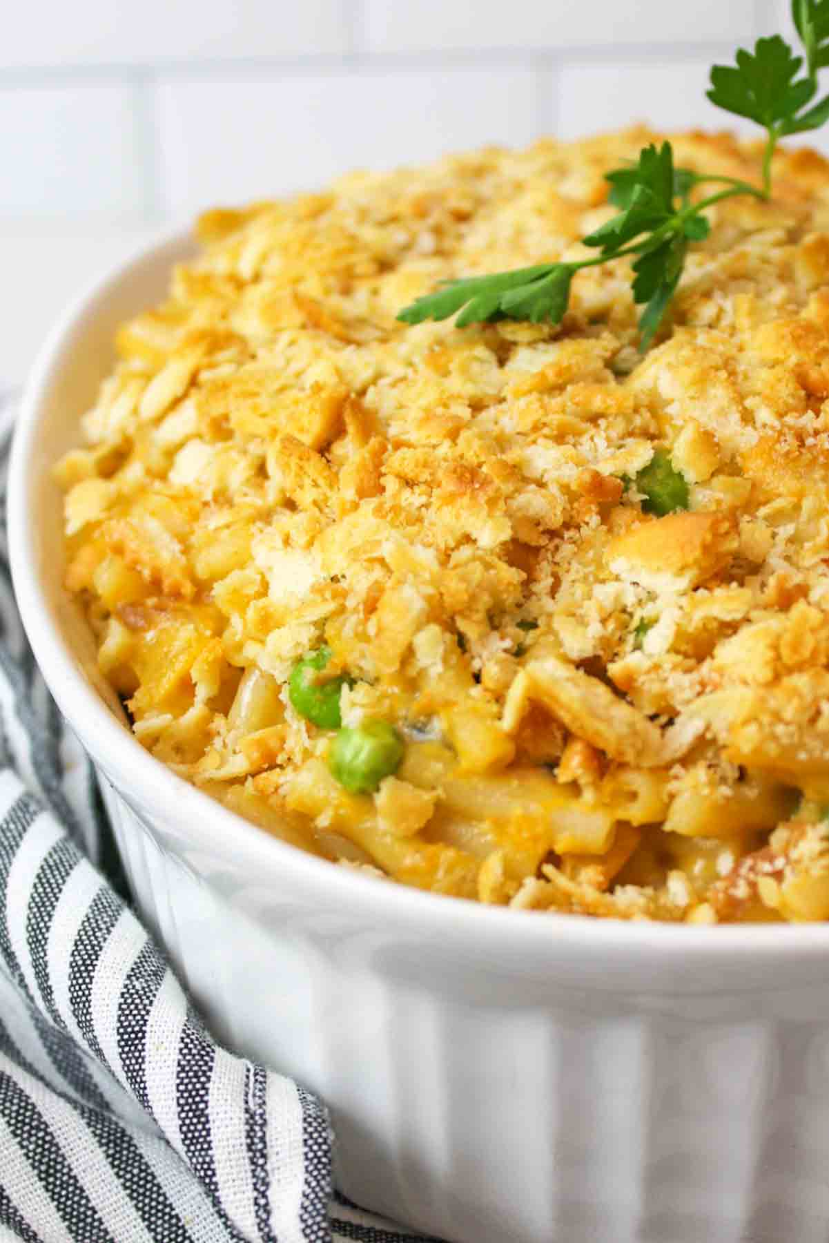 White dish with mac and cheese tuna casserole, topped with fresh parsley.