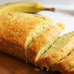 sliced banana bread with a ripe banana in background.