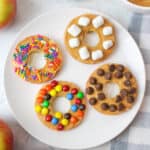 4 apple donuts on a white plate.