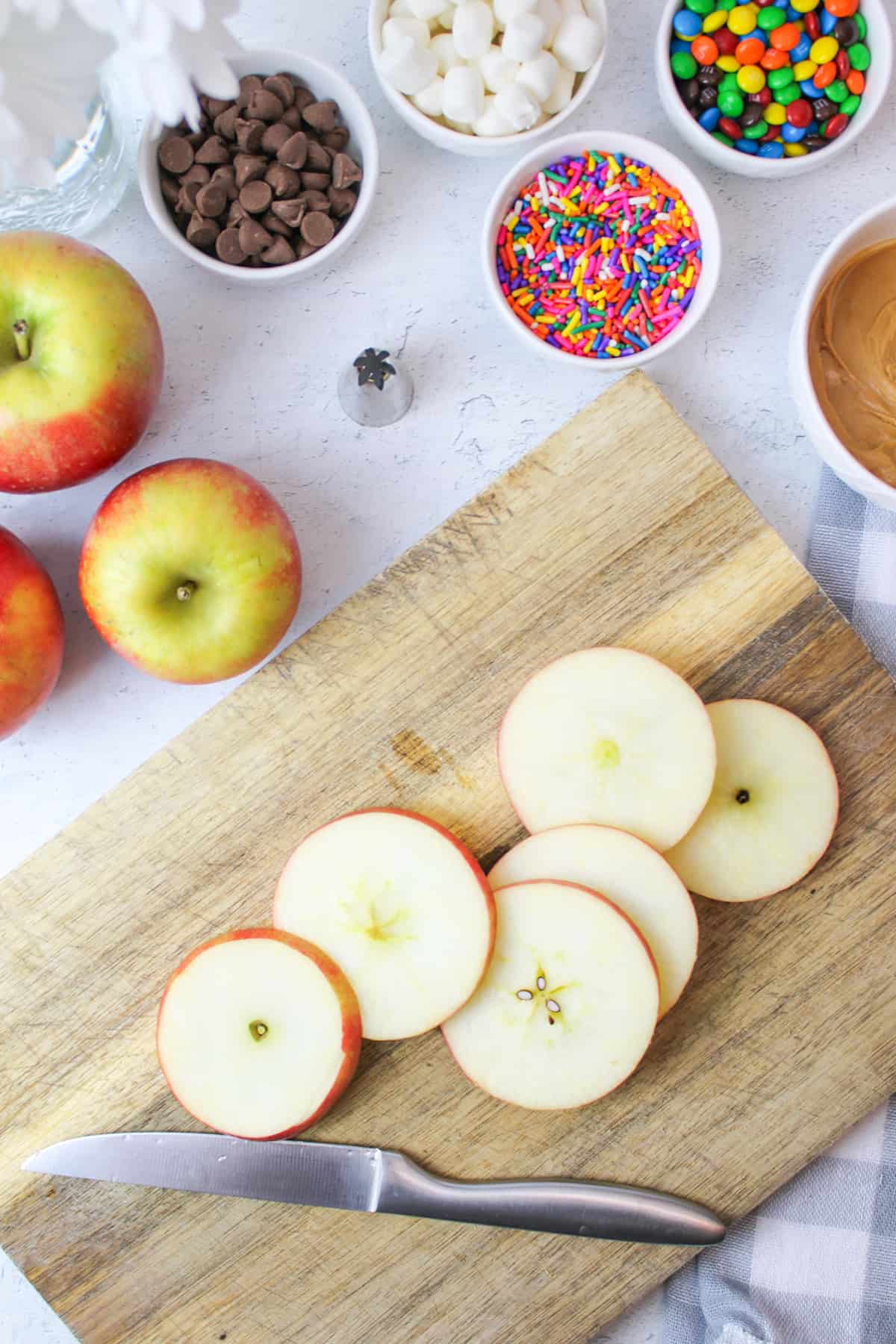 apple on a cutting board with a knife slicing it thinly.