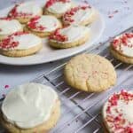 Cherry Chip Cake Mix Cookies with frosting and sprinkles on a wire rack and plate.