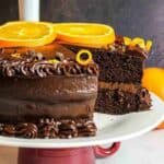 fudgy chocolate orange cake on a plate with slice missing.