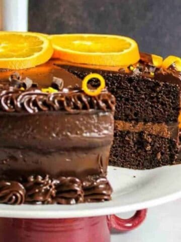 fudgy chocolate orange cake on a plate with slice missing.