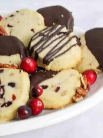 chocolate dipped cranberry shortbread cookies on an oval plate.