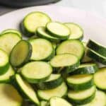 sliced zucchini coins on a white plate.