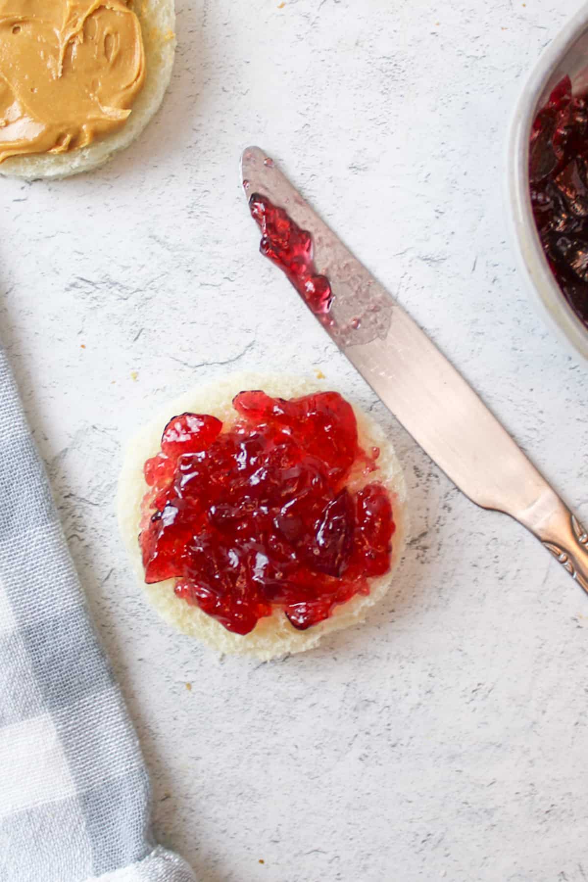 jelly spread on a round piece of bread with a butterknife to the side