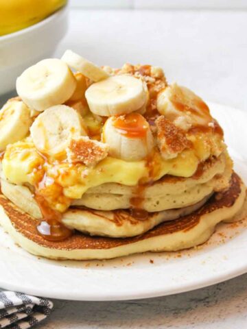 an upclsoe view of salted caramel banana pancakes on a white plate